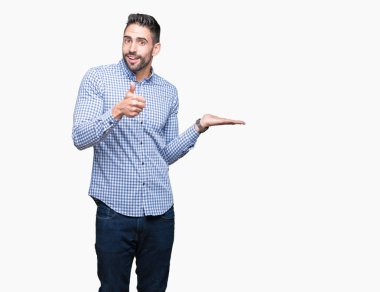 İzole arka plan gösteren palm el ve iş tamam jestle başparmak yukarı, gülümseyen mutlu ve neşeli genç yakışıklı adam