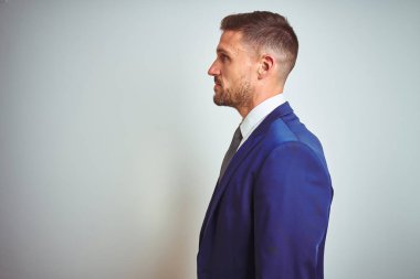 Beyaz izole arka plan üzerinde genç yakışıklı iş adamı yan bakıyor, kendine güvenen gülümseme ile doğal yüzü ile profil poz dinlenmek.