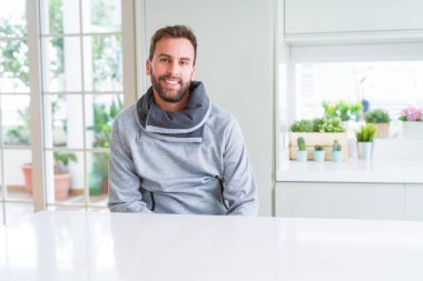 Evde rahat sweatshirt giyen ve olumlu gülümseyen yakışıklı adam