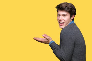 Genç yakışıklı zarif adam izole arka plan üzerinde el ve reklam mutlu ve kendinden emin gülümseyen sunulması avuç, yanında işaret