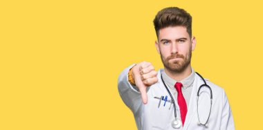 Genç yakışıklı Doktor adam mutsuz ve öfkeli gösteren reddetme ve başparmak aşağı jest ile negatif görünümlü tıbbi ceket giyiyor. Kötü ifade.