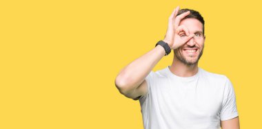 Yakışıklı adam gülümsüyor, parmakları ile mutlu yüz üzerinden seyir göz el ile ok jest yapıyor casual beyaz t-shirt giyen.