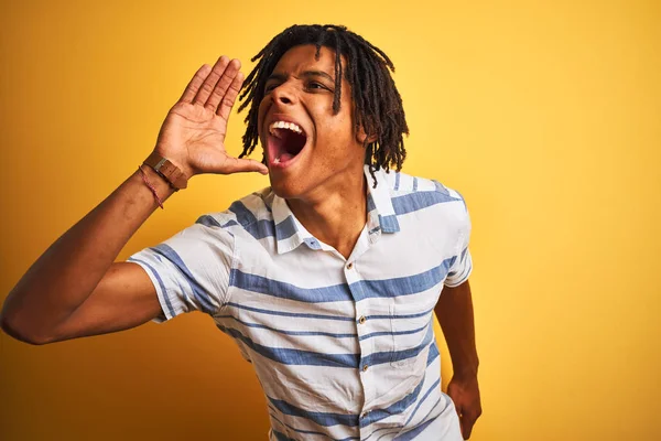 非洲裔美国男子穿着条纹衬衫 在孤立的黄色背景上大喊大叫 用手捂住嘴 大声尖叫 沟通概念 — 图库照片