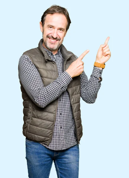中年ハンサムな男着て冬ベスト笑顔で側に つの手と指で指しているカメラ目線 — ストック写真