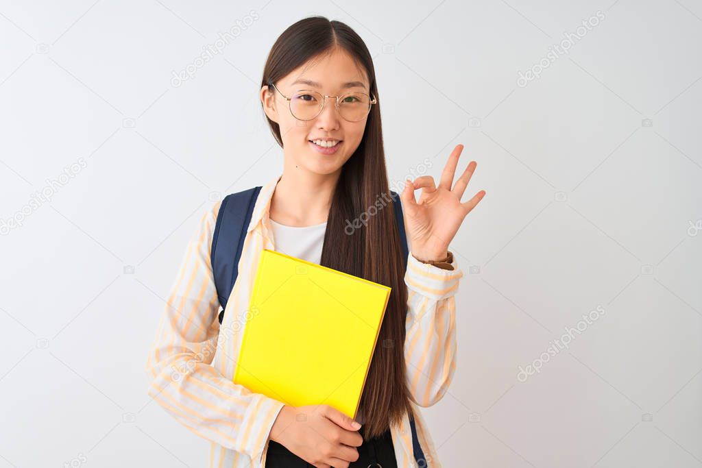 Chinese student woman wearing glasses backpack book over isolated white background doing ok sign with fingers, excellent symbol