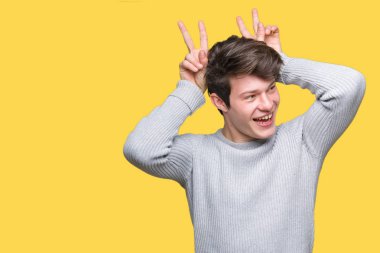 Neşeli gülümseyen izole arka plan tavşan kulakları, komik ve çılgın baş parmaklar ile poz üzerinde kış kazak giyen genç yakışıklı adam