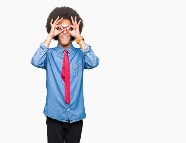 Gözlük ve dilini, parmaklarının arasından baktığını yapışmasını dürbün gibi ok jest yapıyor kırmızı kravat giyen afro saçlı genç Afro-Amerikalı iş adamı. Deli ifade.