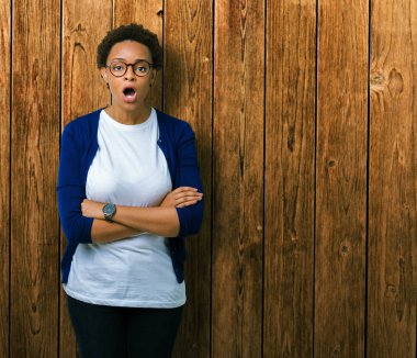 Genç güzel Afrikalı-Amerikalı kadın korkuyor ve şok sürpriz ifade, korku ve heyecan yüz ile izole arka plan üzerinde gözlük.