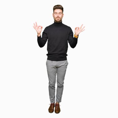 Kış kazak dinlenmek giydiği ve gözleri ile gülümseyen genç yakışıklı sarışın adam parmak ile meditasyon jest yapıyor kapalı. Yoga kavramı.