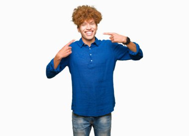 Afro saçlı genç yakışıklı zarif adam emin gösteren gülümseyen ve parmakları diş ve ağız ile işaret. Sağlık kavramı.