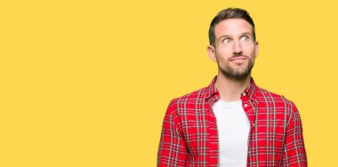 Yakışıklı adam rahat gömlek gülümseyen görünümlü yan ve dik dik bakma uzağa düşünce.