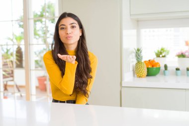 Beyaz masada evde genç güzel kadın kamera hava güzel ve seksi olmak el ile bir öpücük üfleme bakarak. Aşk ifadesi.
