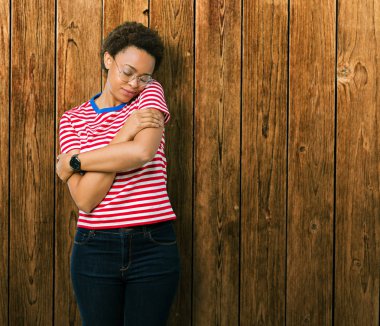 Güzel genç Afro-Amerikan kadın gözlük izole üzerinde emin gülümseyen Hugging kendini mutlu ve olumlu, arka plan. Kendi aşk ve öz bakım