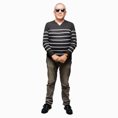 Yüzünde ciddi bir ifade ile kış kazak ve güneş gözlüğü giyen yakışıklı kıdemli adam. Basit ve doğal kamera bakıyor.