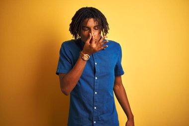 Rahat kot gömlek giyen dreadlocks ile Afro adam izole sarı arka plan üzerinde duran bir şey kokulu ve, dayanılmaz koku, burun parmakları ile nefes tutarak. Kötü kokular kavramı.