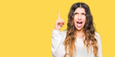 Beyaz kazak işaret parmağı ile başarılı fikir giyen genç güzel kadın. Çıktıktan ve mutlu. Bir numara.