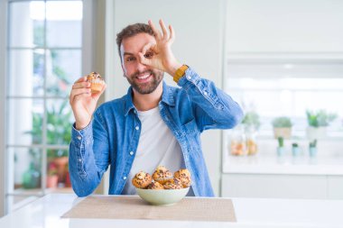 Yakışıklı adam mutlu yüz el parmaklarının arasından seyir göz üzerinde ok işaretiyle yapıyor gülümseyen ile çikolata kek yeme