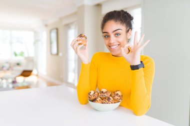 Parmak, mükemmel sembolü ile ok işareti yapıyor çörekler genç Afro-Amerikan kadın yeme çikolata cips