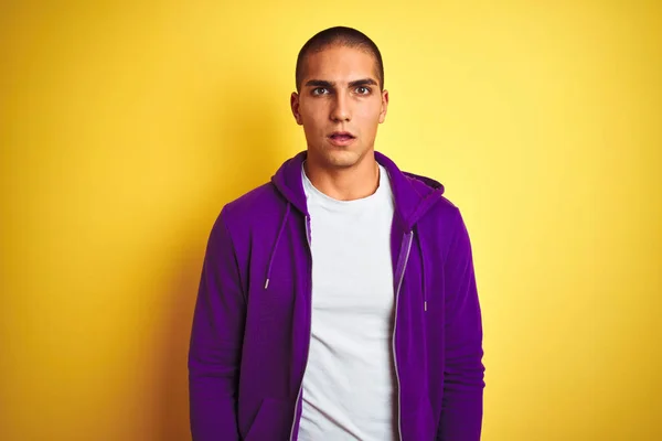 年轻帅哥穿着紫色运动衫在黄色孤立的背景害怕和震惊与惊讶的表情 恐惧和兴奋的脸 — 图库照片