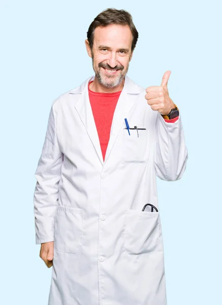 穿着白色外套的中年治疗师用手做着快乐的大拇指 通过显示成功来批准镜头的表达 — 图库照片