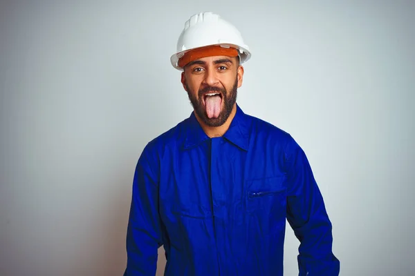 制服とヘルメットをかぶったハンサムなインド人労働者の男は 面白い表情で舌を突き出す孤立した白い背景の上に 感情の概念 — ストック写真