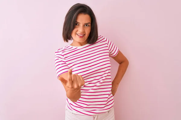 Young beautiful woman wearing striped t-shirt standing over isolated pink background Beckoning come here gesture with hand inviting welcoming happy and smiling