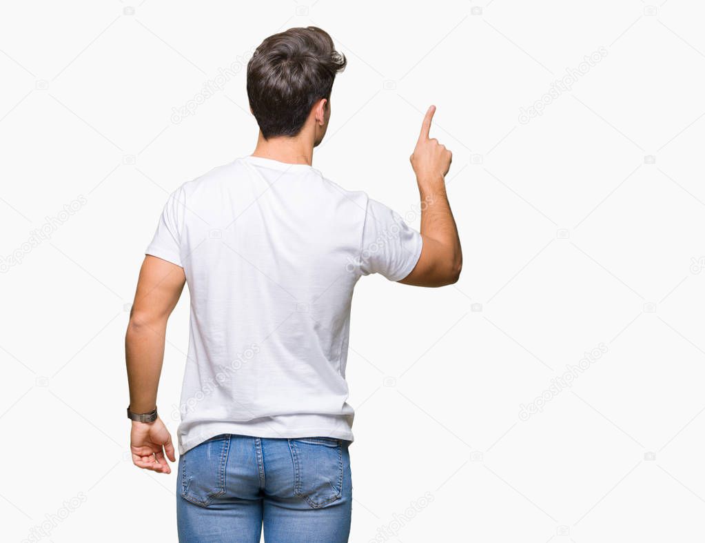 Young handsome man wearing white t-shirt over isolated background Posing backwards pointing behind with finger hand