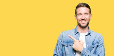 Yakışıklı adam mavi gözleri ve denim ceket neşeli bir gülümseme ile el ve parmak kadar yan yüzünde mutlu ve doğal ifade ile işaret yüz sakal