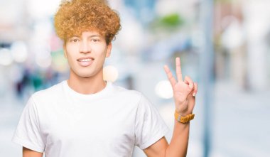 Gösterilen ve parmakları ile işaret casual beyaz t-shirt giyen afro saçlı yakışıklı delikanlı ikincisi ise kendinden emin ve mutlu gülümseyerek.