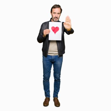 Açık eliyle dur işareti ile ciddi ve kendine güvenen ifade, savunma jest yapıyor kırmızı kalp ile kağıt tutan yakışıklı orta yaş erkek