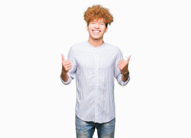 Genç yakışıklı iş adamı el ile olumlu hareketi yaparken şık gömlek başarı işareti giyiyor afro saçlı başparmak gülümseyen ve mutlu. Neşeli bir ifadeyle, kazanan jest kameraya bakıyor.