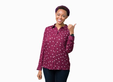 Seyir ve başparmak yanında yukarıyı mutlu yüz ile gülümseyen izole arka plan üzerinde başörtüsü giyen güzel genç Afro-Amerikan kadın.