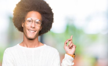 Kameraya bakarak yan el ve parmak ile işaret eden genç Afro-Amerikan adam afro saçlı gözlüklü kocaman bir gülümseme ile yüzünde,.