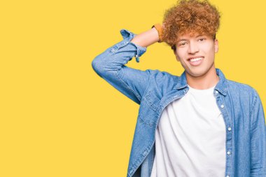 Denim ceket Gülen hareketi, el ile'deki emin dokunaklı saç giyen afro saçlı Genç yakışıklı adam çekici poz