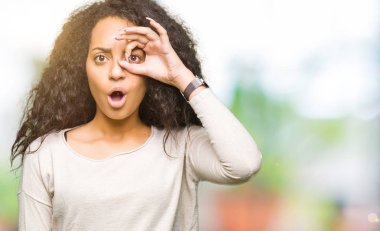 Kıvırcık saç ile genç güzel kız rahat kazak yaparken Sürpriz yüz ile şok ok jest yapıyor, göz parmaklar bakarak. İnanılmaz ifade.