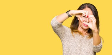 Kalp simgesi ve elleriyle şekil gösterilen aşık gülümseyen moda kazak giyen güzel orta yaş kadın. Romantik kavramı.