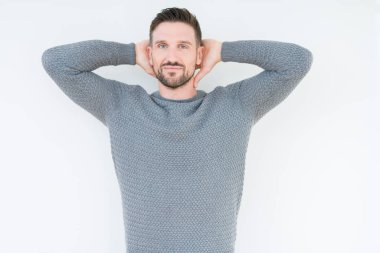 Genç yakışıklı adam izole arka plan üzerinde rahat kazak giyen rahatlatıcı ve kollar ve eller baş ve boyun arkasında uzanan, mutlu gülümseyen
