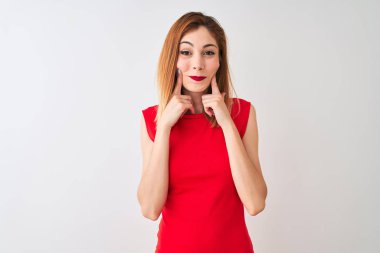 Izole beyaz arka plan üzerinde duran zarif kırmızı elbise giyen Redhead iş kadını açık ağız ile gülümseyerek, parmakları işaret ve neşeli gülümseme zorluyor