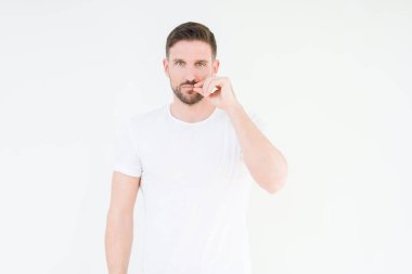 Üzerinde rahat beyaz t-shirt giyen genç yakışıklı adam arka plan ağız izole ve parmak ile ZIP olarak Dudaklarını kapa. Gizli ve sessiz, tabu söz