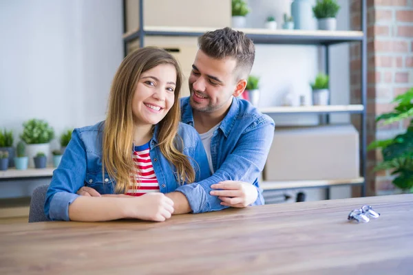Young beautiful couple sitting on the table at home, hugging in