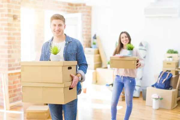 Hermosa pareja joven sonriendo en amor sosteniendo cajas de cartón , — Foto de Stock