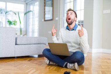 Yakışıklı adam bilgisayar dizüstü bilgisayar kullanarak çalışan giyen şaşırttı ve baktı ve parmakları ile işaret ve kolları kaldırdı şaşırttı.