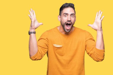 Yakışıklı delikanlı deli kutluyor ve silah ile başarı için heyecanlı çığlık kaldırdı ve açık gözleri hayret izole arka plan üzerinde. Kazanan kavramı