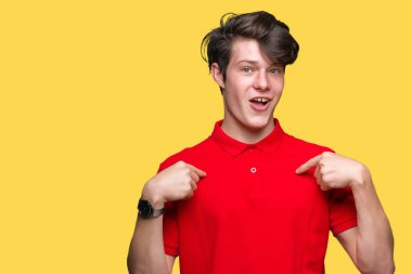 İzole arka plan üzerinde kırmızı t-shirt giyen genç yakışıklı adam yüzünde gülümseme ile kendine güvenen görünümlü, parmaklarıyla gurur ve mutlu kendini işaret.