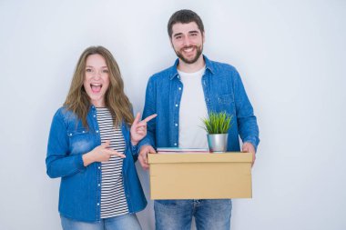 Genç çift tutan karton kutu beyaz izole arka plan üzerinde yeni eve hareket çok mutlu el ve parmak ile işaret