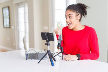 Genç afro-amerikan kadın akıllı telefon kamera ve mikrofon kullanarak görüntülü arama yapıyor mutlu yüz görünümlü ve başparmak ile yan işaret gülümseyerek.