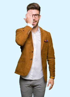 El yüz ve sürpriz duygu kendinden emin gülümseme ile tek gözüyle kapsayan gözlüklü genç yakışıklı iş adamı.