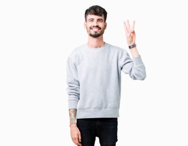 Gösterilen arka plan üzerinde sweatshirt giyen genç yakışıklı adam izole ve parmakları ile işaret üçüncü gülümseyen ise kendinden emin ve mutlu.