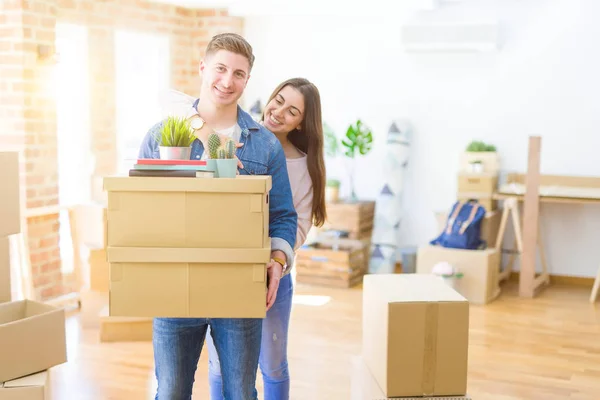 Hermosa pareja joven sonriendo en amor sosteniendo cajas de cartón , — Foto de Stock