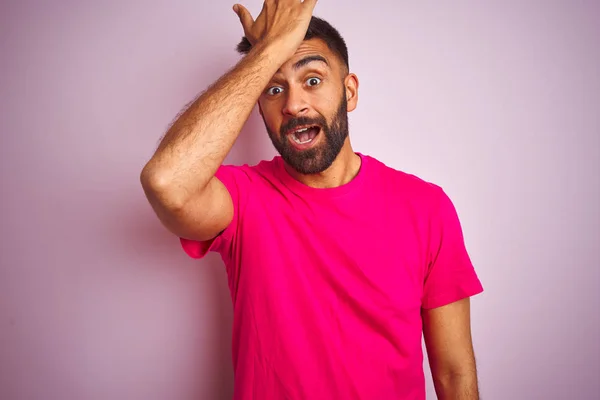 孤立したピンクの背景の上に立つTシャツを着た若いインド人男性は 間違って頭の上に手で驚いた エラーを覚えています 忘れられた 悪いメモリの概念 — ストック写真